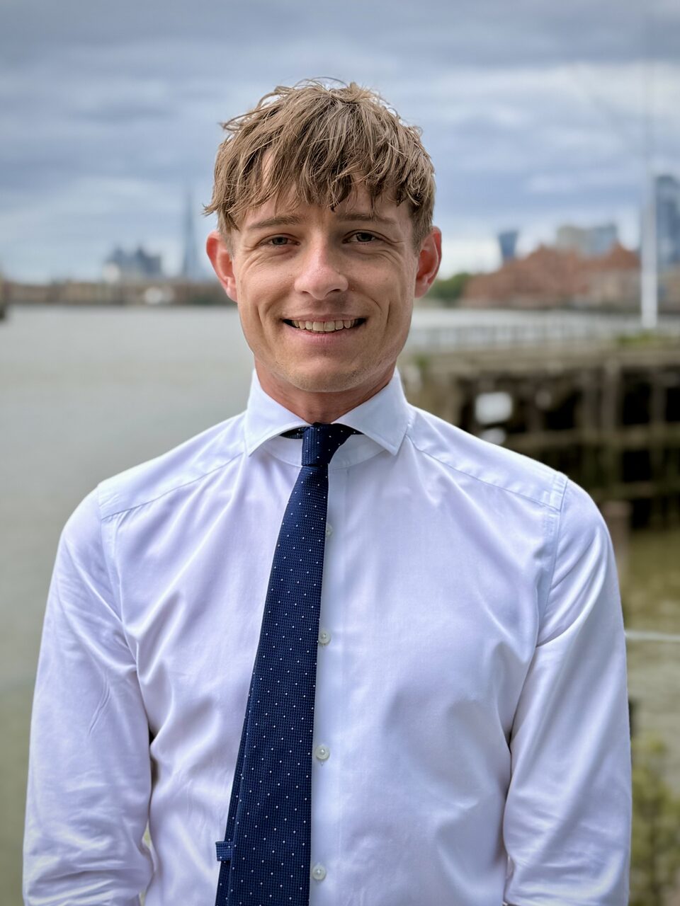 Andrew Morris, founder of Port Phones, on the Thames with the City of London skyline behind him
